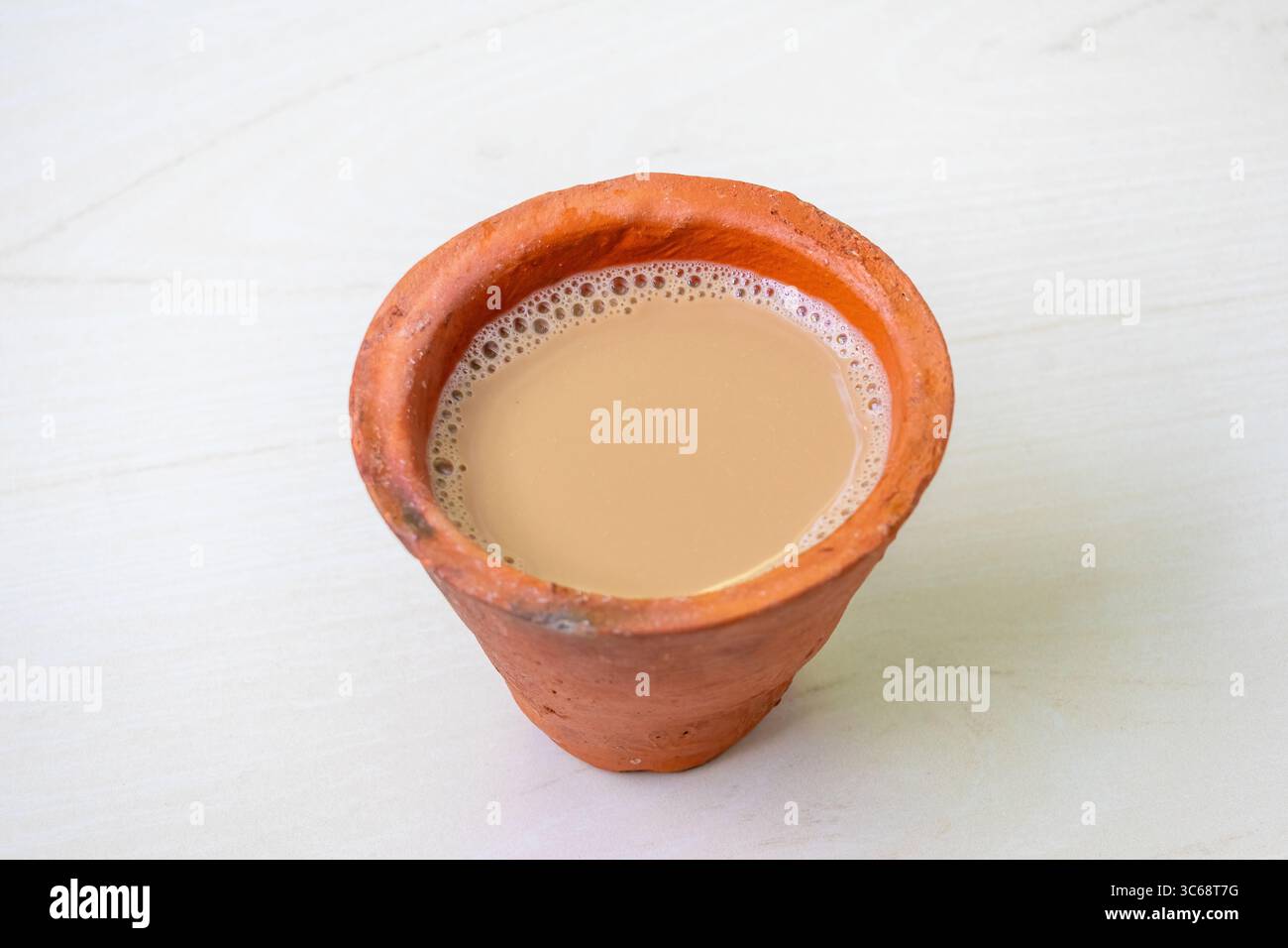 Una tazza di tè al latte o di Dudh Cha, servita in una tazza di argilla su una superficie di legno chiaro. Foto Stock