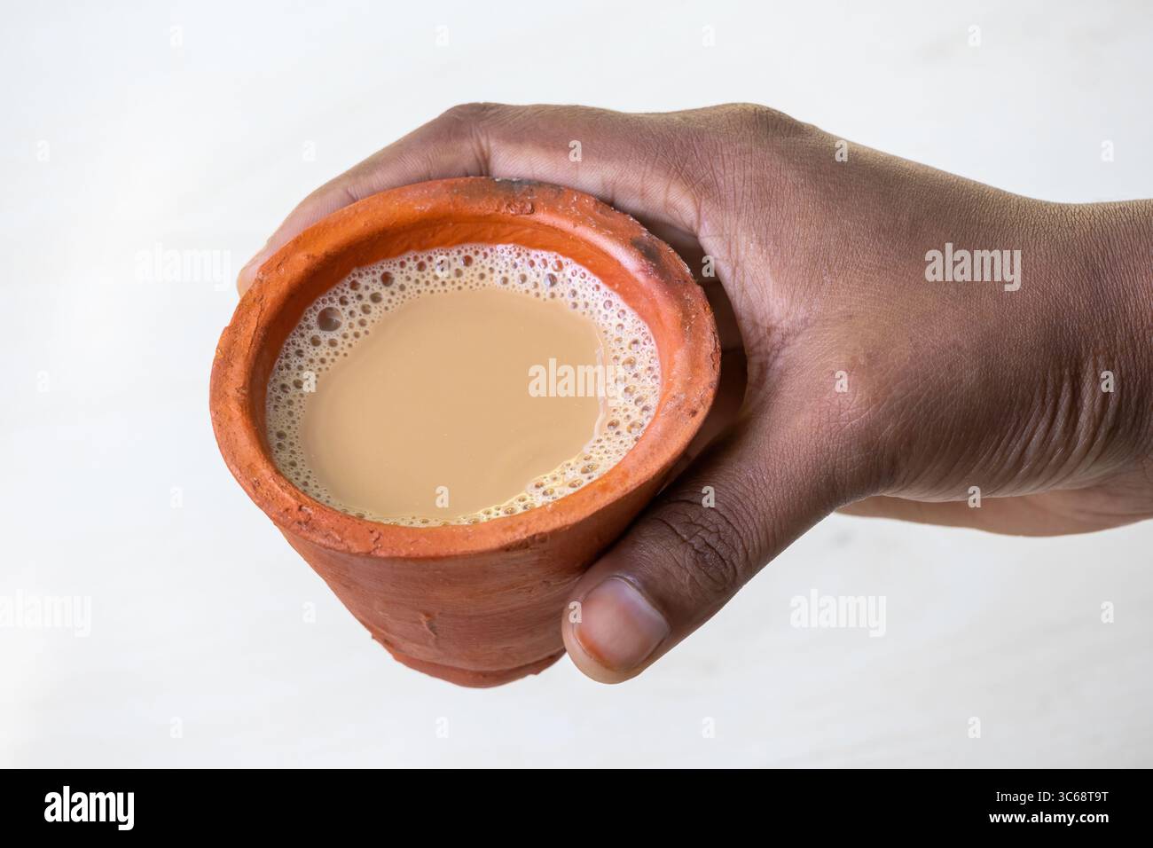 La mano di una donna regge una tazza di masala caldo chai o Kadak Chai in una tradizionale tazza di argilla. Foto Stock