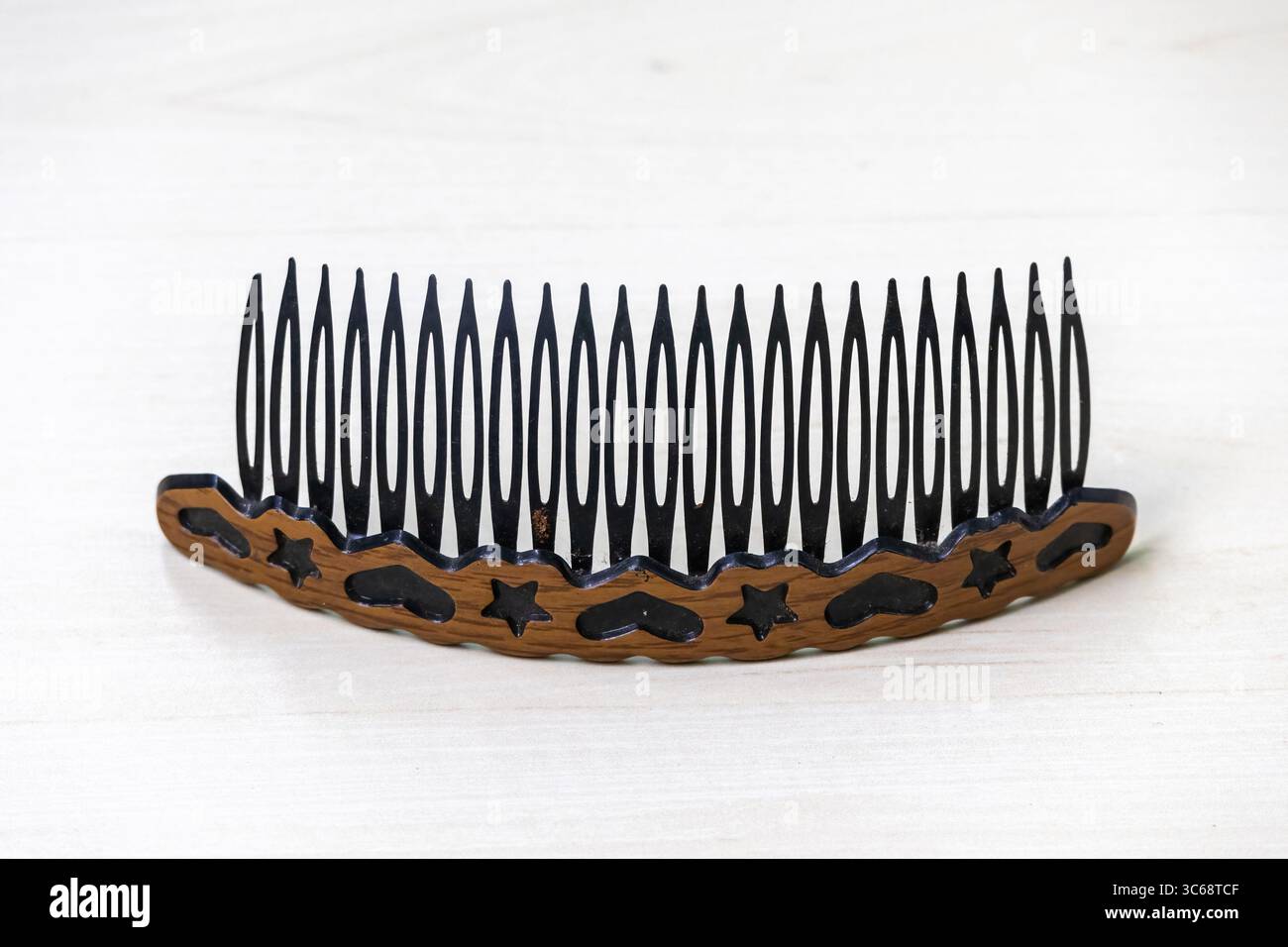 Un pettine o una fascia in plastica poggiano su una superficie di legno chiaro. Questi sono accessori per capelli da donna. Foto Stock