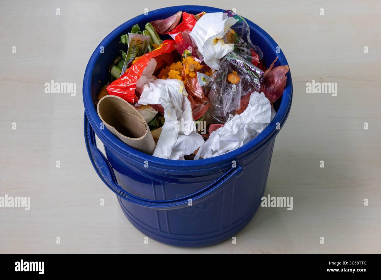 Il secchio di plastica blu è pieno di rifiuti domestici e rifiuti. Foto Stock