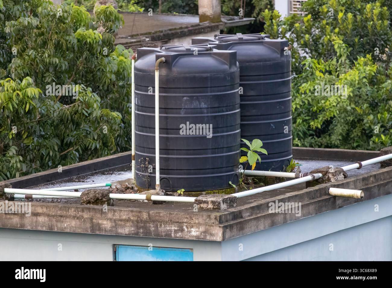 Serbatoi d'acqua in plastica nera sul tetto di una casa in Bangladesh. Foto Stock