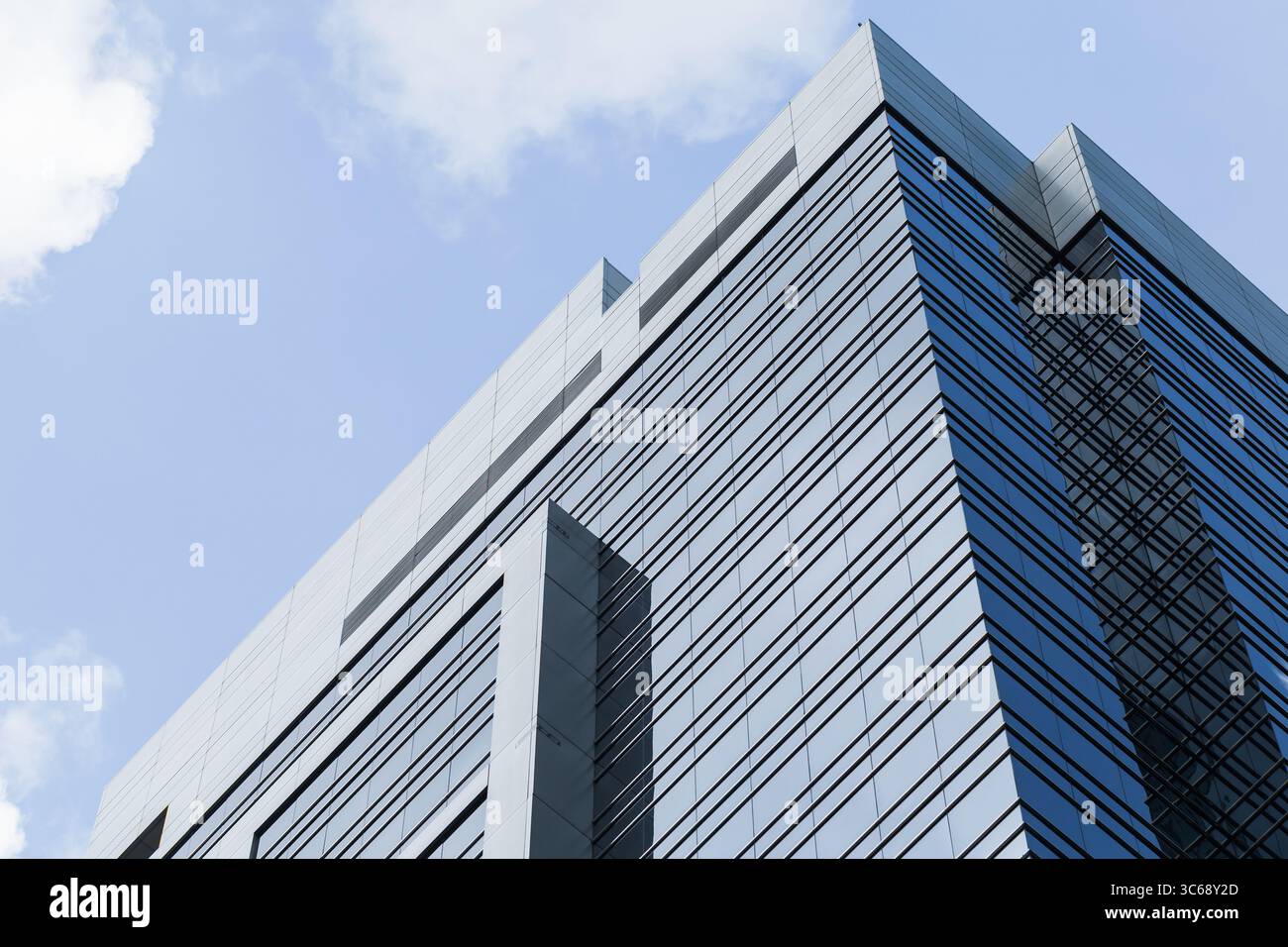 Un design architettonico contemporaneo caratterizzato da un grattacielo rivestito in vetro che si erge su uno sfondo di cielo azzurro, simboleggiando innovazione, progresso, A. Foto Stock