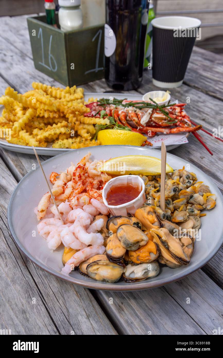 Piatto di pesce a Osbournes, Leigh-on-Sea, Essex, Regno Unito: Aragosta, gamberi, cozze, patatine fritte e spicchi di limone serviti durante il pranzo estivo. Foto Stock