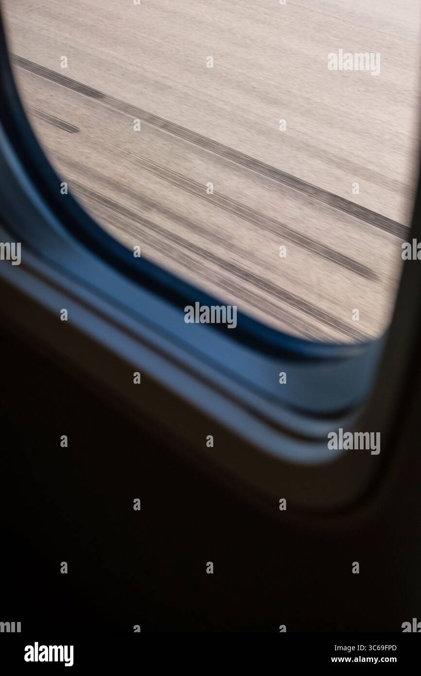 Vista dal finestrino di un aeromobile al decollo con segni di scorrimento neri sulla pista lasciata dagli altri pneumatici dell'aeromobile. Foto Stock