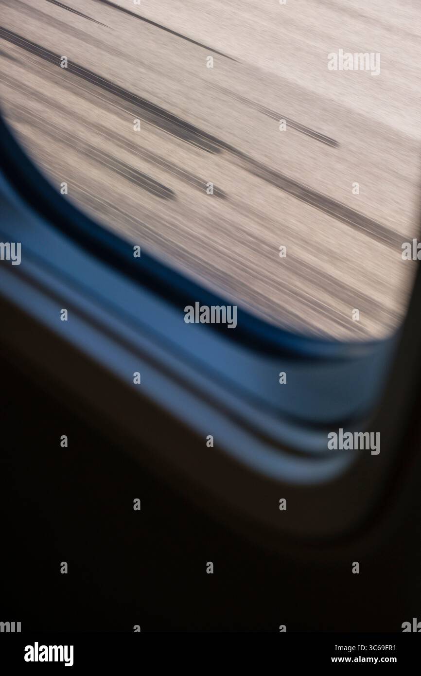 Vista dal finestrino di un aeromobile al decollo con segni di scorrimento neri sulla pista lasciata dagli altri pneumatici dell'aeromobile. Foto Stock