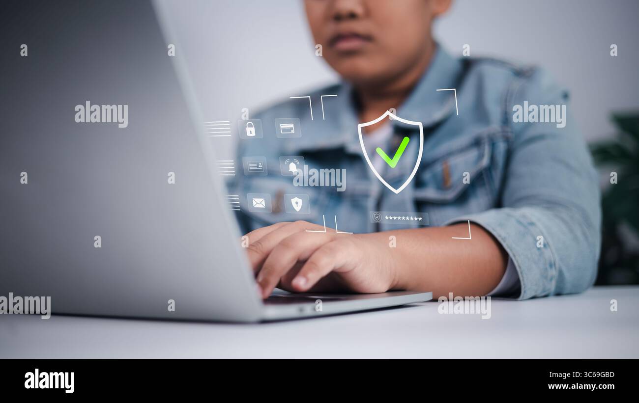 Concetto di sicurezza informatica che mostra un ragazzo asiatico che utilizza un laptop con interfaccia digitale, simboleggia la sicurezza online, la privacy dei dati e la protezione di Internet dei bambini. Foto Stock