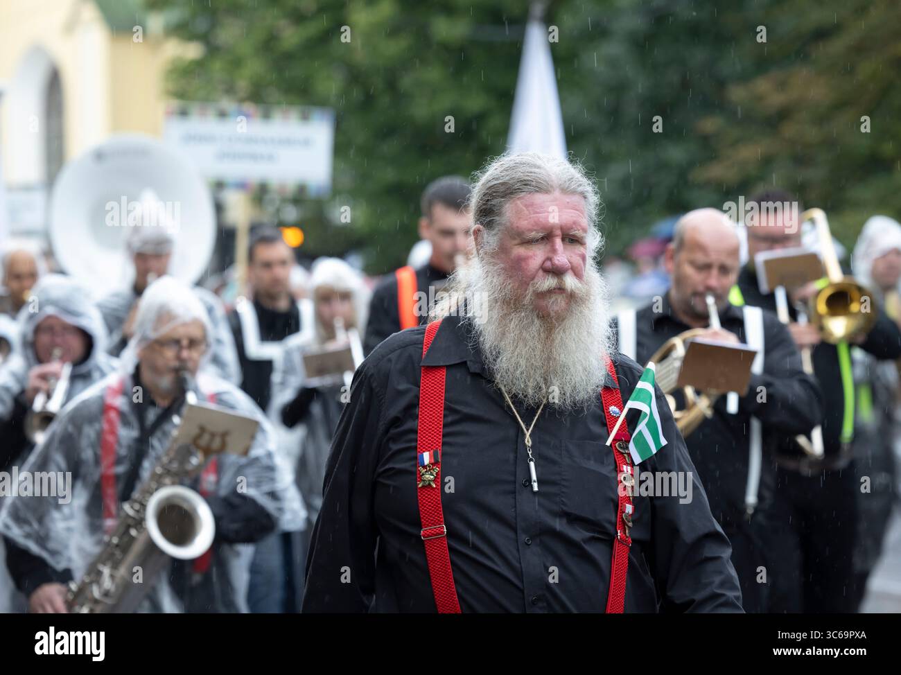 Tallinn, Estonia, 4 luglio 2025: Persone in abbigliamento tradizionale e sotto la pioggia per le strade di Tallinn durante il famoso festival della canzone e della danza, Foto Stock