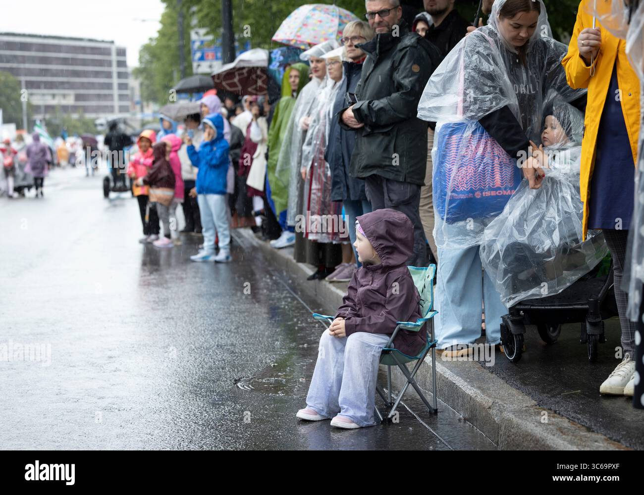 Tallinn, Estonia, 4 luglio 2025: Persone in abbigliamento tradizionale e sotto la pioggia per le strade di Tallinn durante il famoso festival della canzone e della danza, Foto Stock