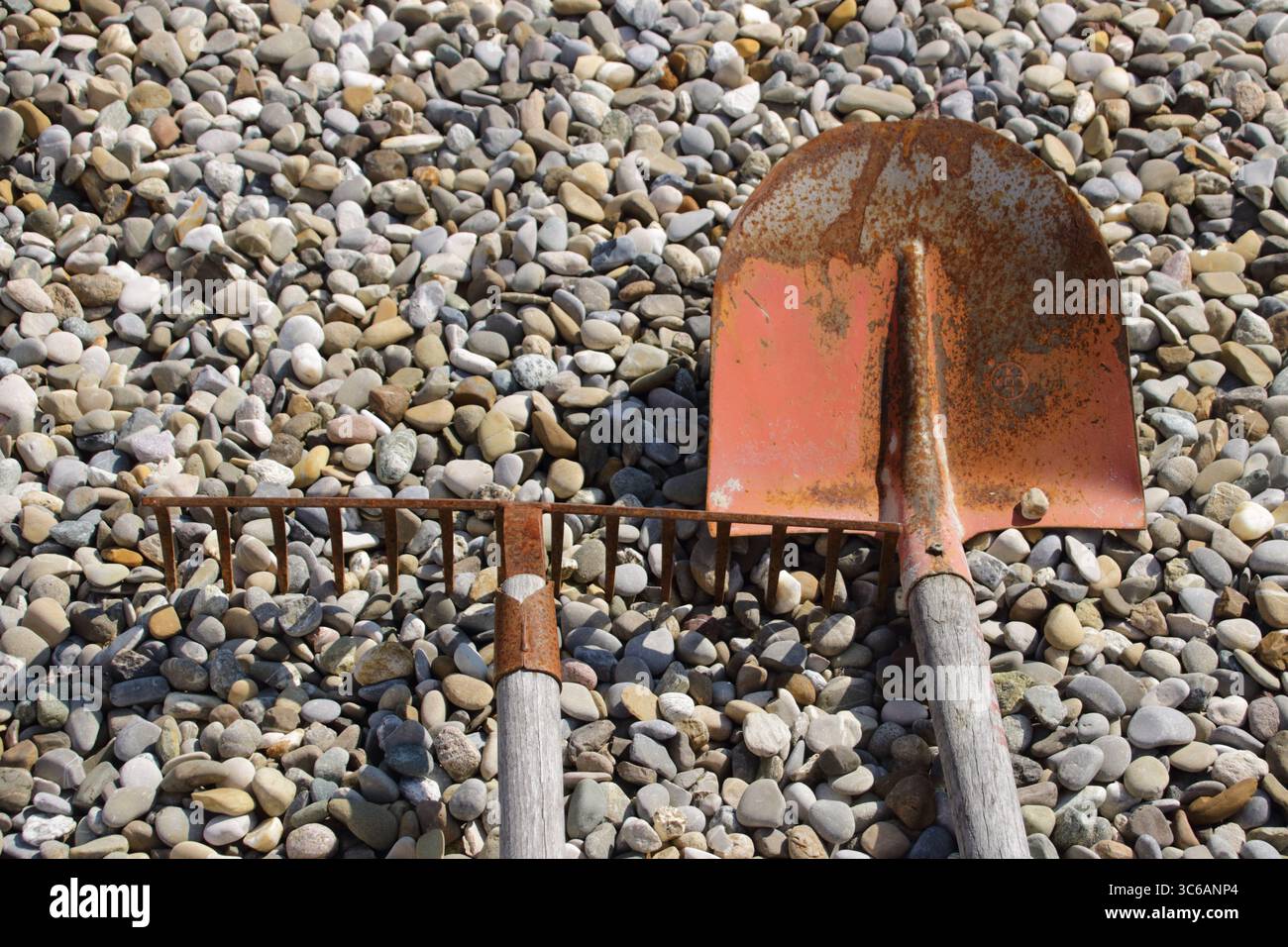 La pala e il rastrello si trovano uno accanto all'altro sulla ghiaia Foto Stock