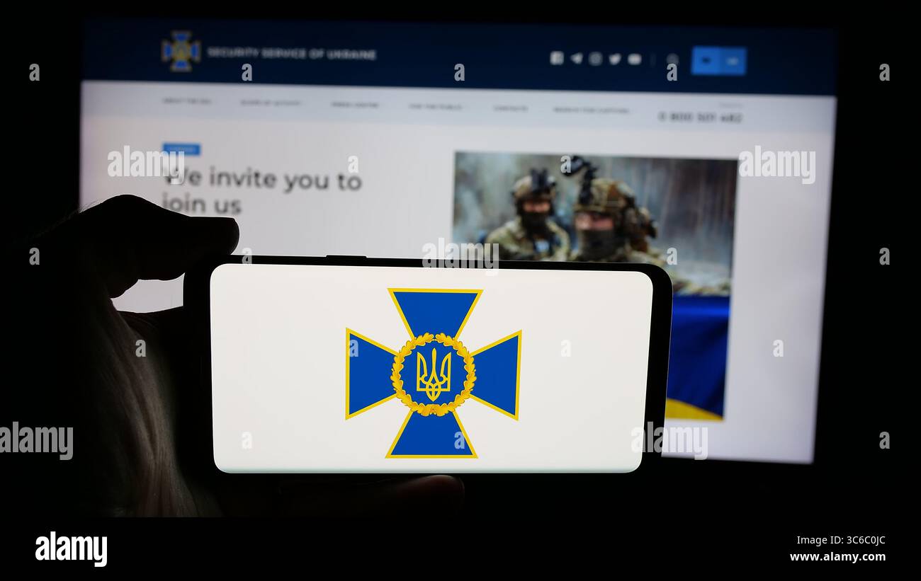 Stoccarda, Germania - 06-18-2025: Persona che tiene il cellulare con il logo del servizio di sicurezza Sluzhba Bezpeky Ukrainy SBU sullo schermo di fronte alla pagina web. Foto Stock