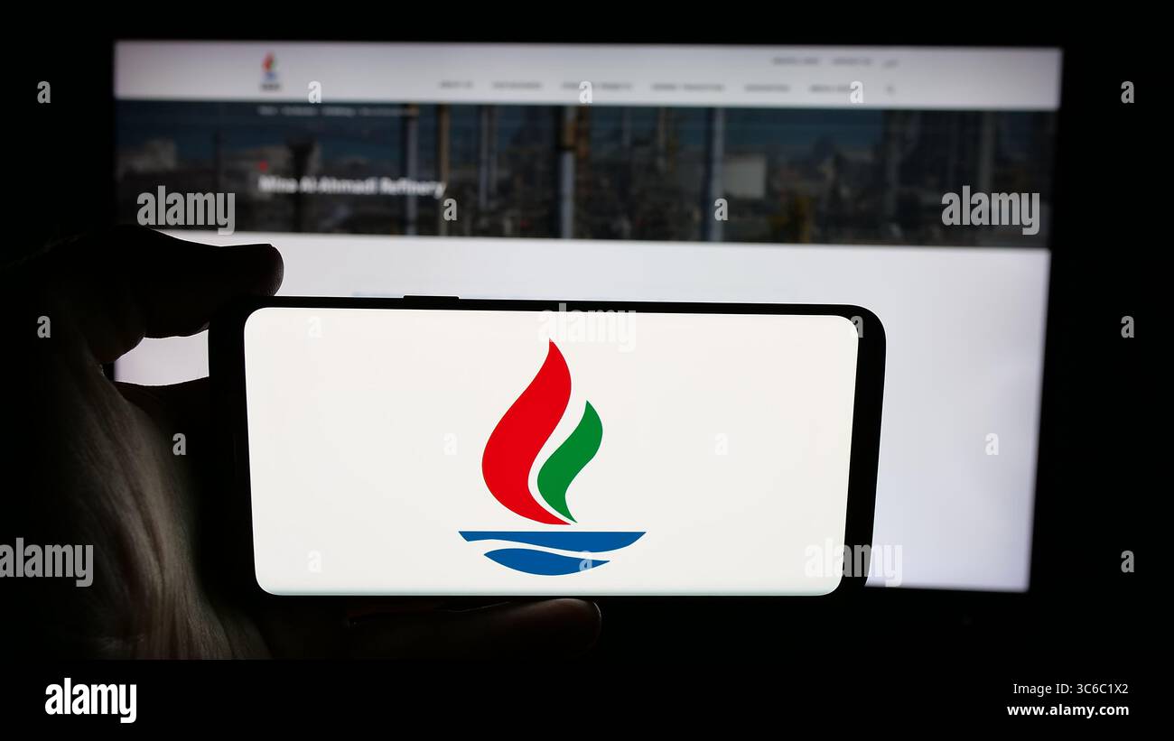 Stoccarda, Germania - 06-18-2025: Persona che tiene il cellulare con il logo della Kuwait National Petroleum Company (KNPC) sullo schermo davanti alla pagina web. Foto Stock