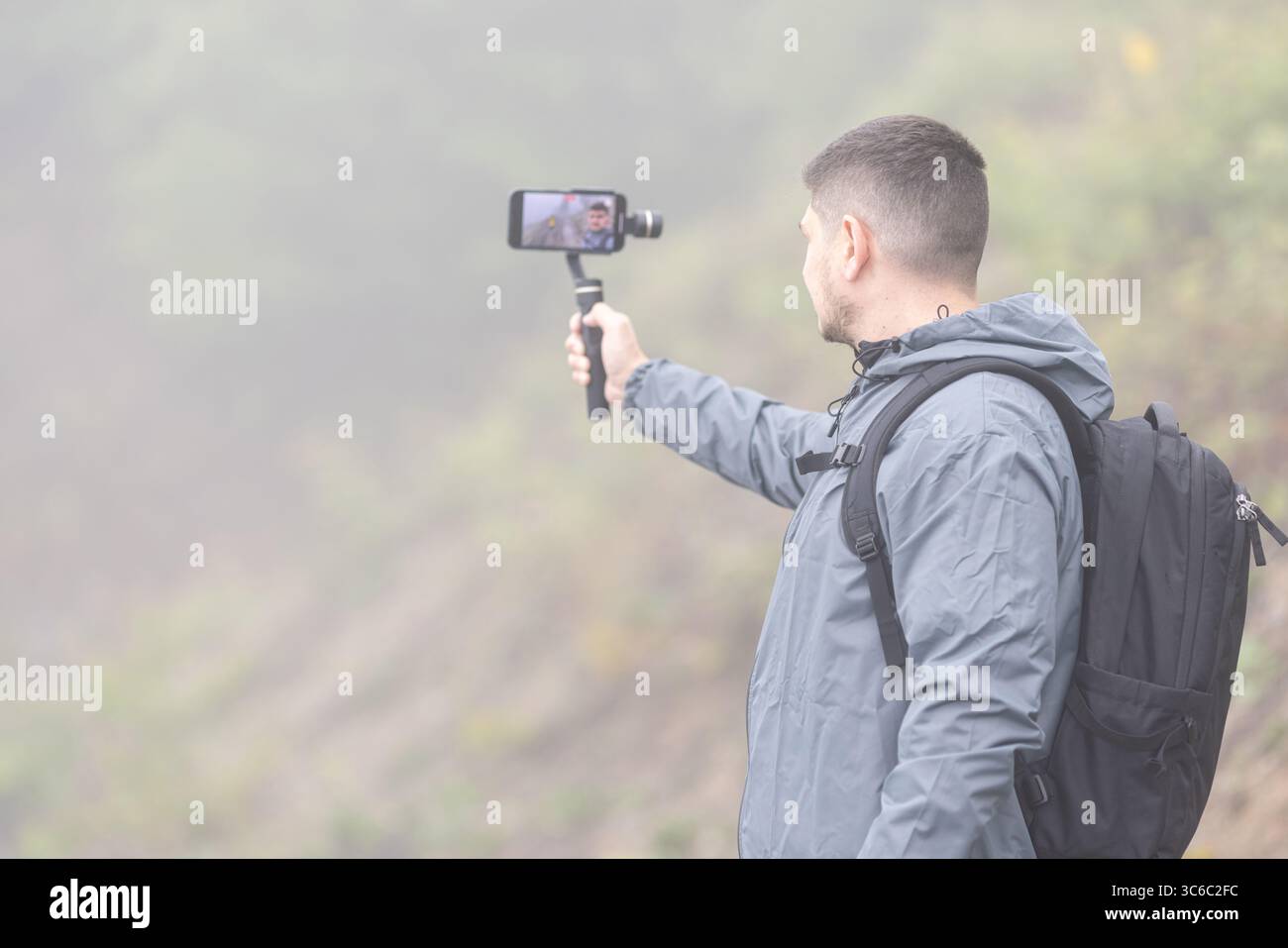 Un uomo registra un video per un blog in una giornata nebbiosa Foto Stock