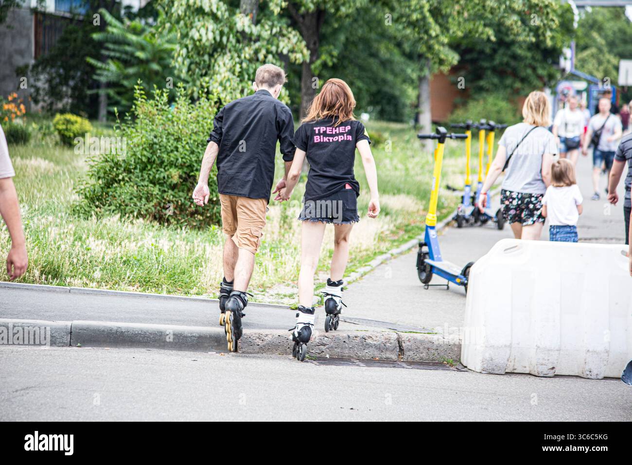 Estate 2023 luglio, un giovane ragazzo ama pattinare a rotelle sulla strada di Kiev nella regione di Obolon, con l'istruttore di pattinaggio a rotelle Viktoria Foto Stock