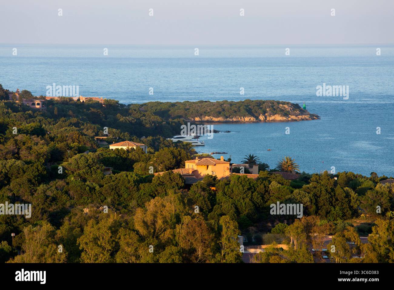 Porto Cervo, Costa Smeralda, Gallura, Sardegna, Italia. Vista sulla costa boscosa dalla cima della collina, lussuose case illuminate dal sole al tramonto. Foto Stock