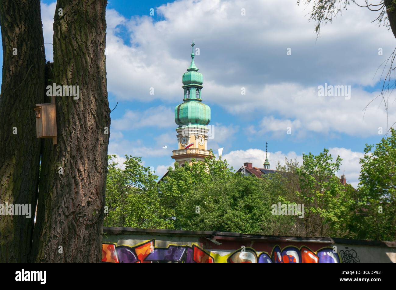 Torre con un caratteristico elmetto della Chiesa di Santa Maria Maddalena, casa degli uccelli sull'albero. Tychy, Polonia. Foto Stock