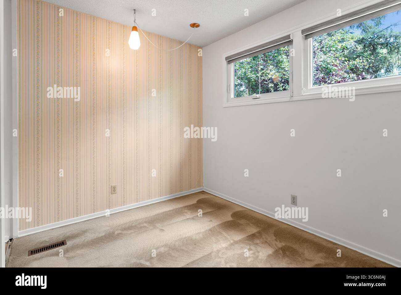 Camera piccola con un muro bianco e una carta da parati a righe. La camera è vuota e ha un aspetto pulito e minimalista Foto Stock