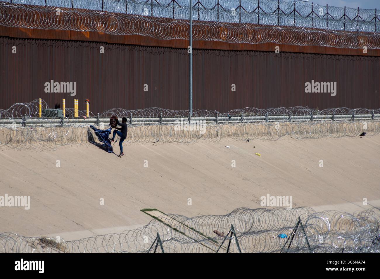 Due persone adattano un grande tessuto come parte di un'installazione artistica vicino al recinto di confine di Ciudad Juarez, simboleggiando i problemi di migrazione. Foto Stock