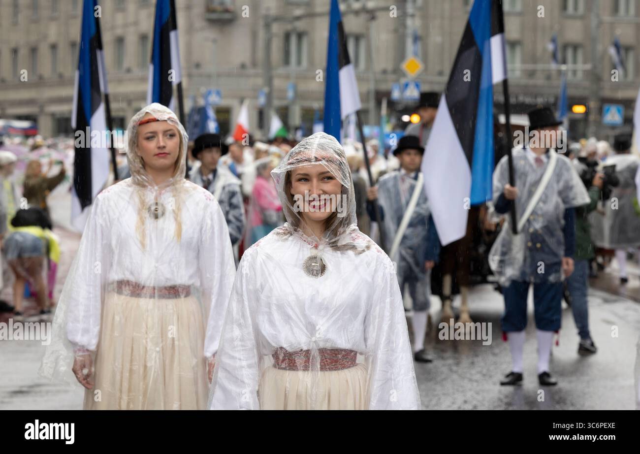 Tallinn, Estonia, 4 luglio 2025: Persone in abbigliamento tradizionale e con cappotti antipioggia per le strade di Tallinn durante il famoso festival di canto e danza Foto Stock