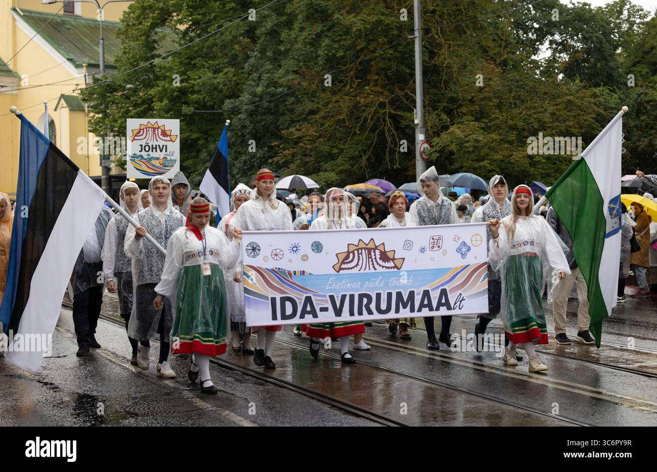 Tallinn, Estonia, 4 luglio 2025: Persone in abbigliamento tradizionale e sotto la pioggia per le strade di Tallinn durante il famoso festival della canzone e della danza, Foto Stock
