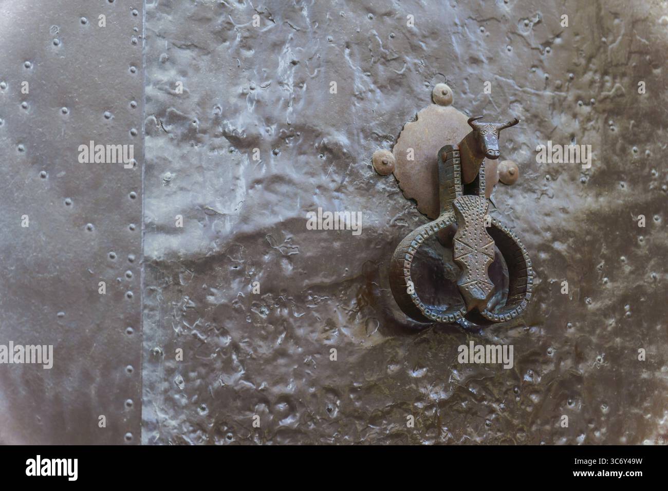 Ronda, malaga, spagna primo piano di un'antica porta di metallo caratterizzata da un caratteristico bussone a forma di toro, che mette in risalto gli effetti del tempo e degli agenti atmosferici Foto Stock