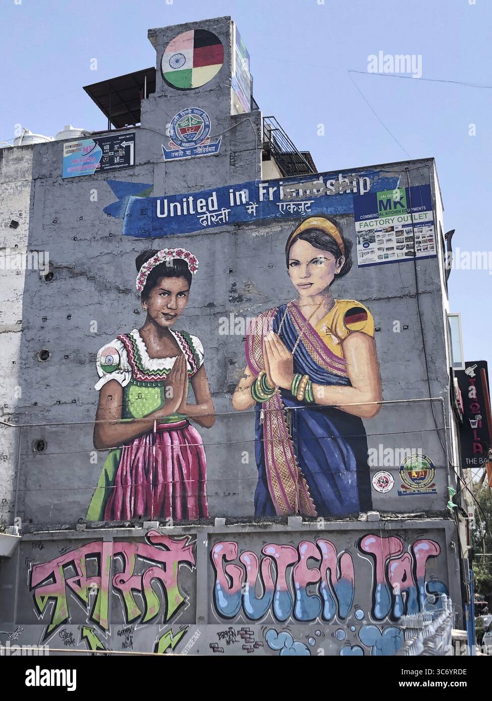 Pittura murale di due donne in abito tradizionale, una donna indiana in un dirndl bavarese, una donna tedesca in un sari, nuova Delhi, India Foto Stock