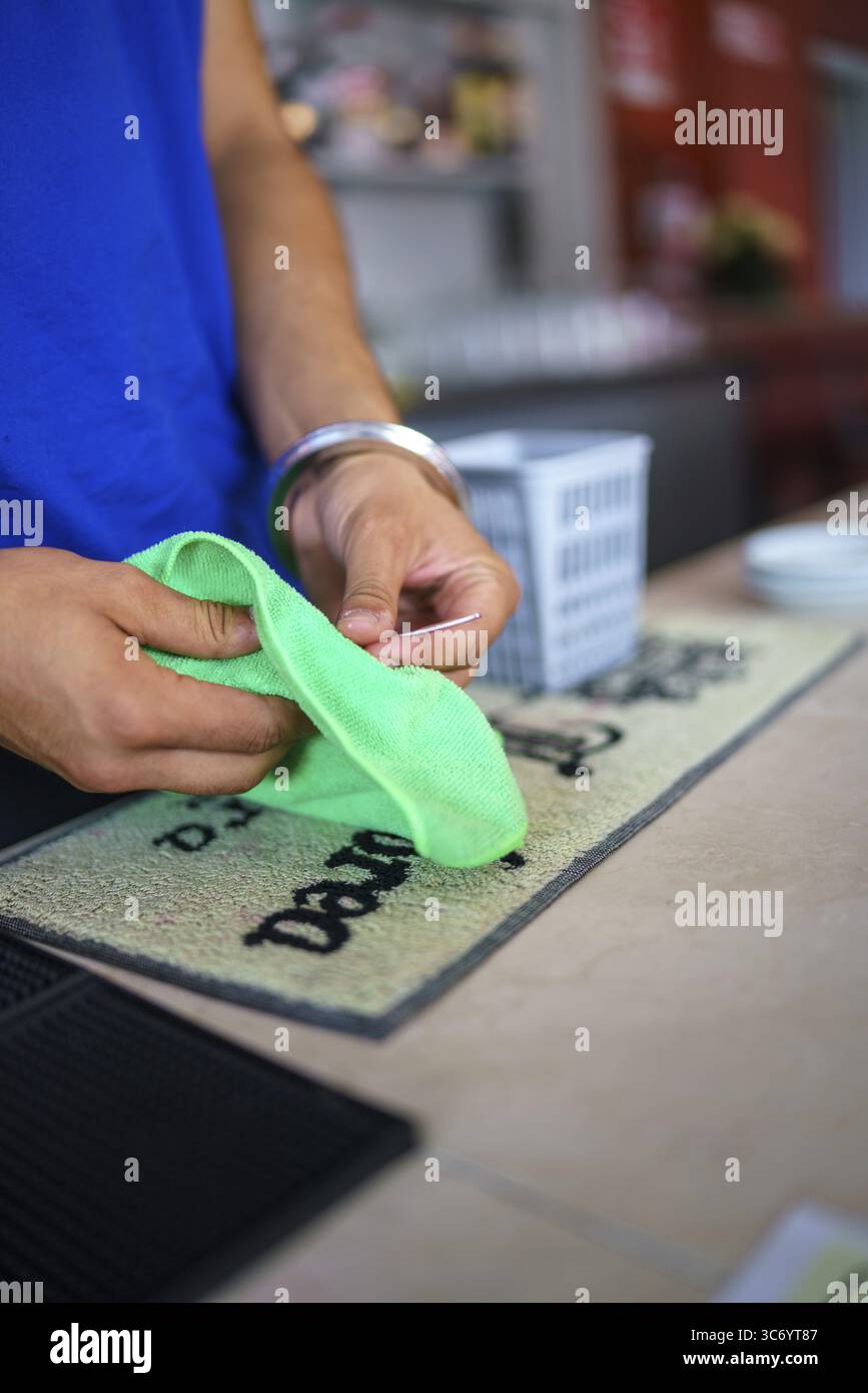 Pulizia delle mani di una superficie con un panno verde su un tappetino da bar, Cremona, Italia 25 luglio 2025 Foto Stock