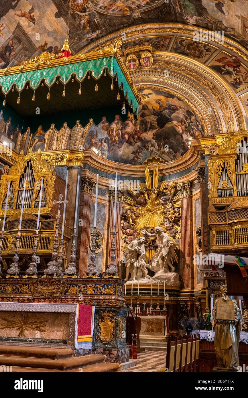 Altare maggiore all'interno della concattedrale di San Giovanni a la Valletta, Malta, altare maggiore con la scultura del Battesimo di Cristo, abside dipinta e baldacchino. Foto Stock
