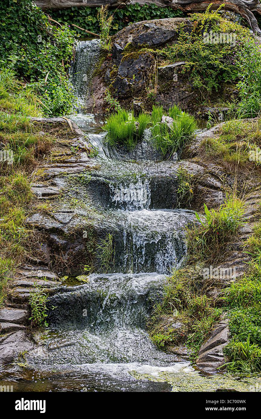 Cascata a più livelli che scende su rocce muschiose Foto Stock