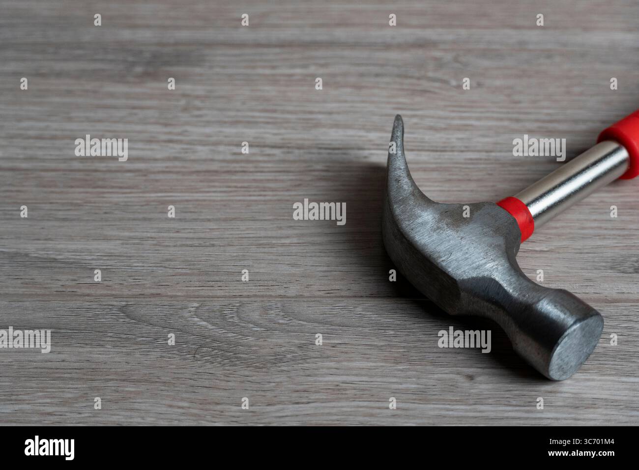 Immagine ravvicinata di un martello a baionetta con testa metallica e impugnatura rossa posizionata su una superficie in legno Foto Stock