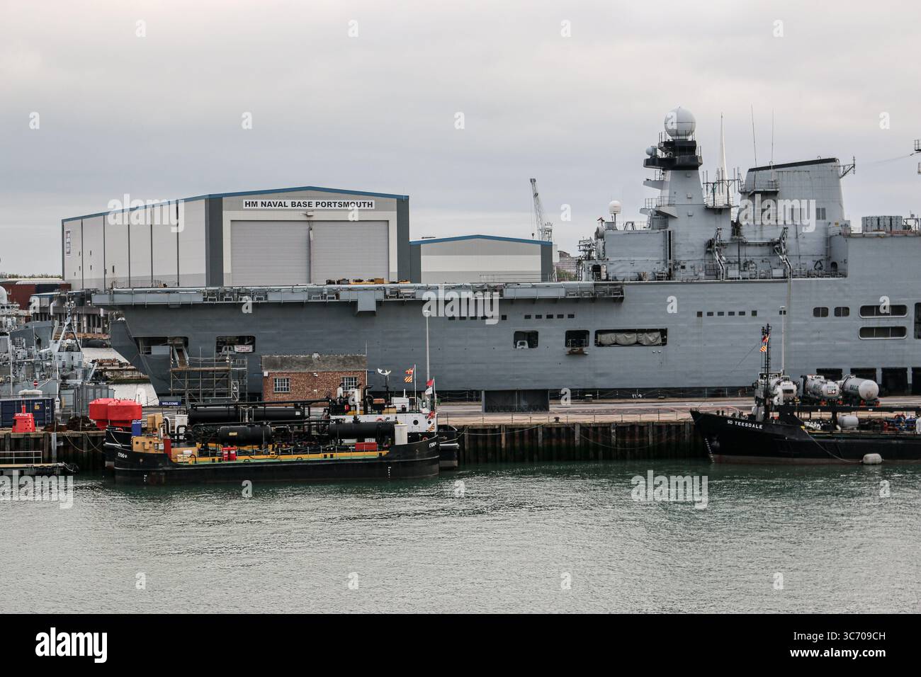 HM Naval base Portsmouth, Regno Unito: La portaerei leggera della Royal Navy HMS ILLUSTRIOUS (R06) | compensazione delle chiatte ausiliarie (RMA poi Serco) Foto Stock