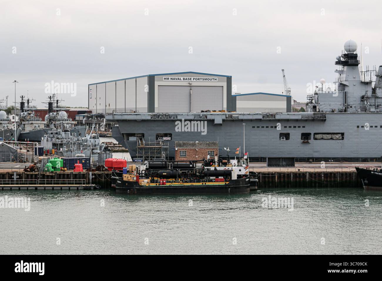 HM Naval base Portsmouth, Regno Unito: La portaerei leggera della Royal Navy HMS ILLUSTRIOUS (R06) | compensazione delle chiatte ausiliarie (RMA poi Serco) Foto Stock