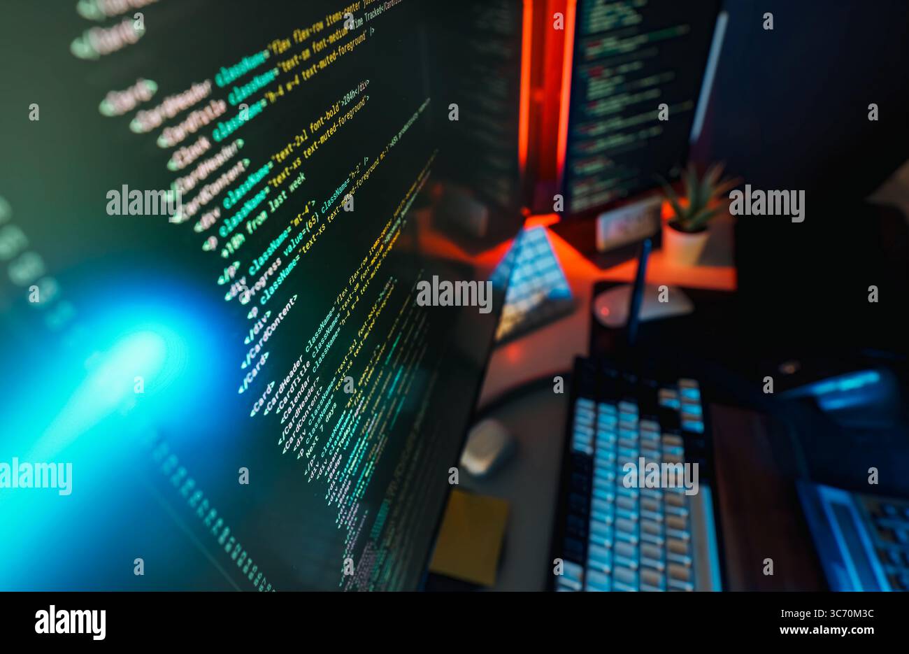 Spie al neon della schermata del codice dell'area di lavoro del programmatore. Schermo computer moderno e ravvicinato con codice di programmazione colorato, illuminato da un ambiente blu e rosso Foto Stock