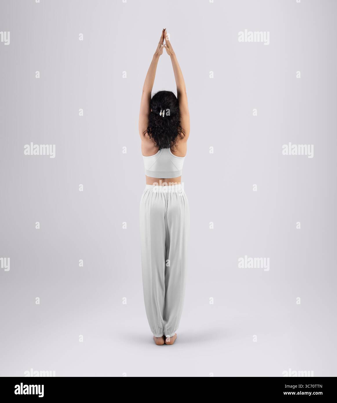 Mockup di pantaloni sciolti bianchi con fasce elastiche, tuta da allenamento yoga su una donna in asana, vista posteriore, a tutta lunghezza. Modello di pantaloni larghi per design, reggiseno Foto Stock