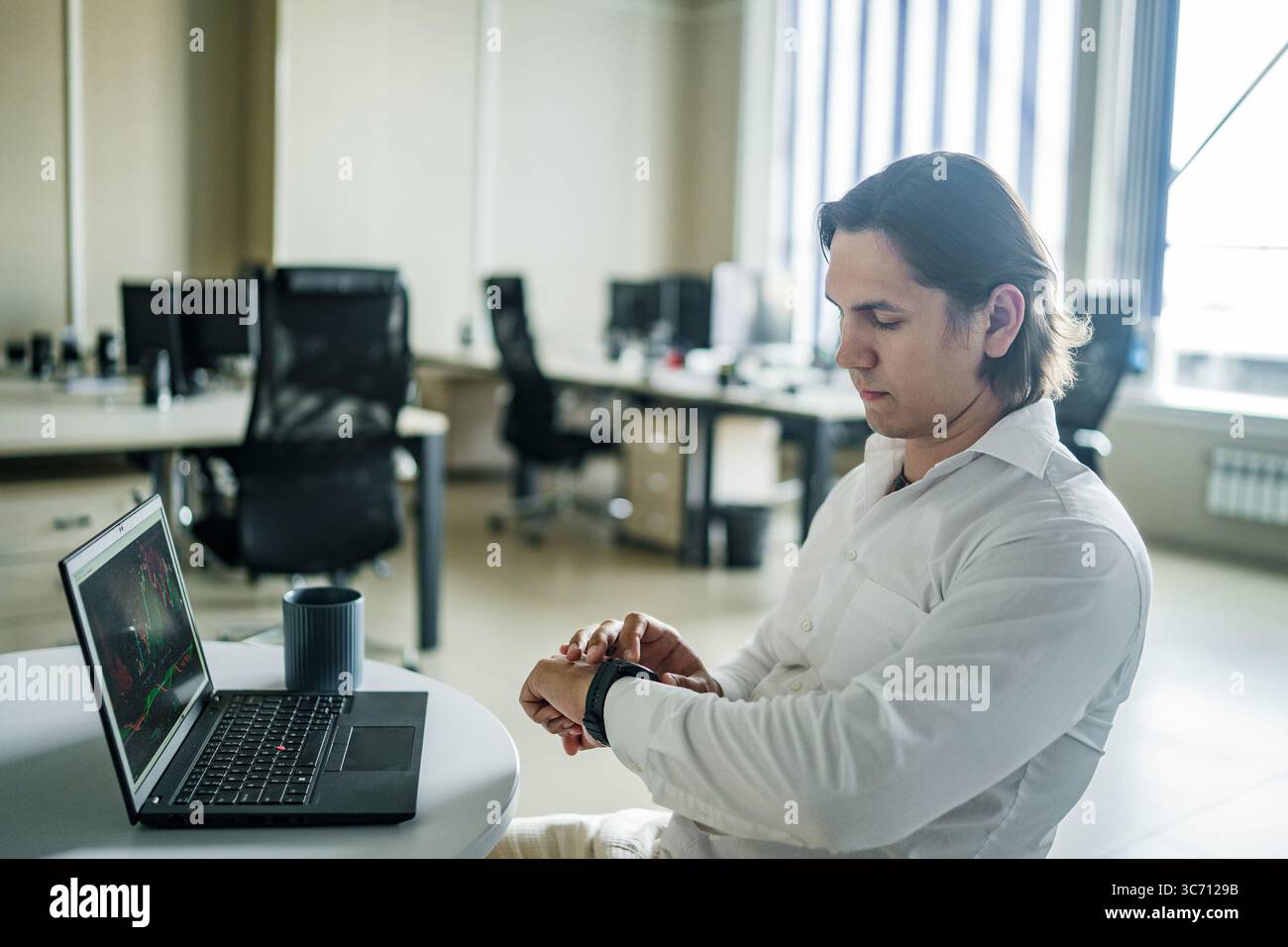 L'uomo controlla l'orologio intelligente durante la pausa caffè in un ufficio moderno. Foto Stock