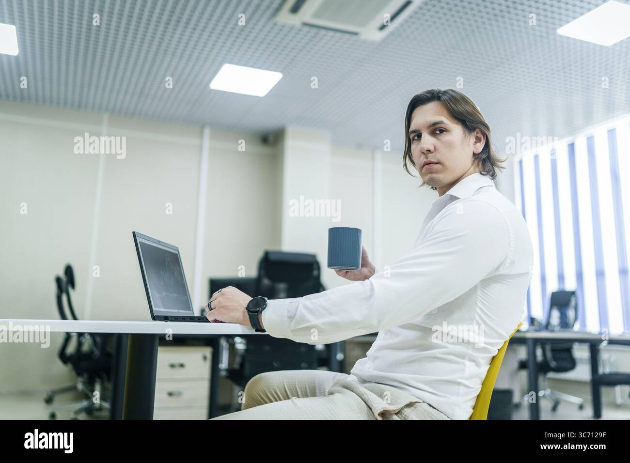Man analizza le analisi con il caffè in un ufficio luminoso. Foto Stock