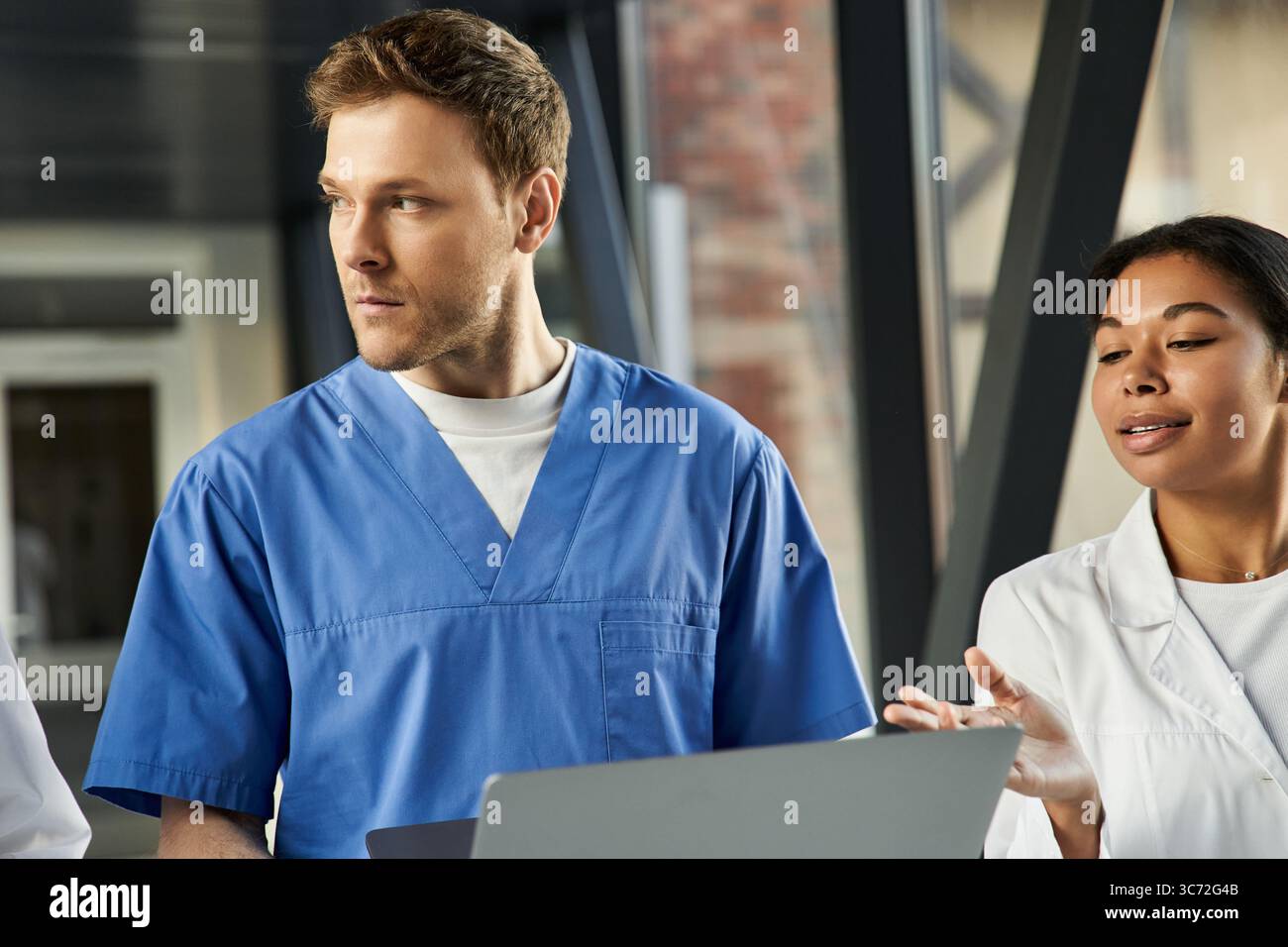 Tre medici si impegnano in una vivace discussione in un ambiente ospedaliero contemporaneo. Foto Stock