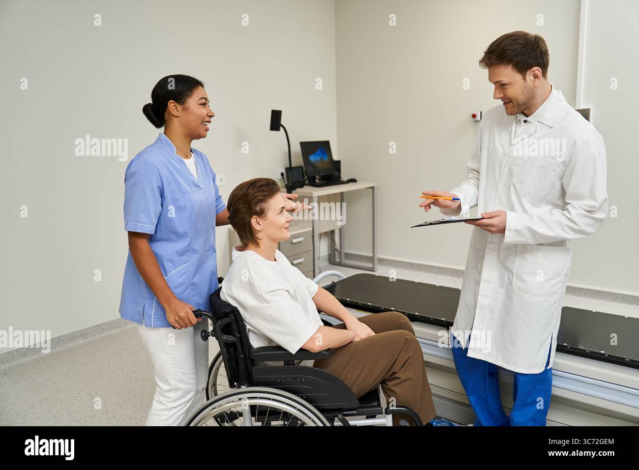 L'equipe medica assiste la paziente in sedia a rotelle per una scansione RM presso una struttura moderna. Foto Stock L'equipe medica assiste la paziente in sedia a rotelle per una scansione RM presso una struttura moderna. Foto Stock