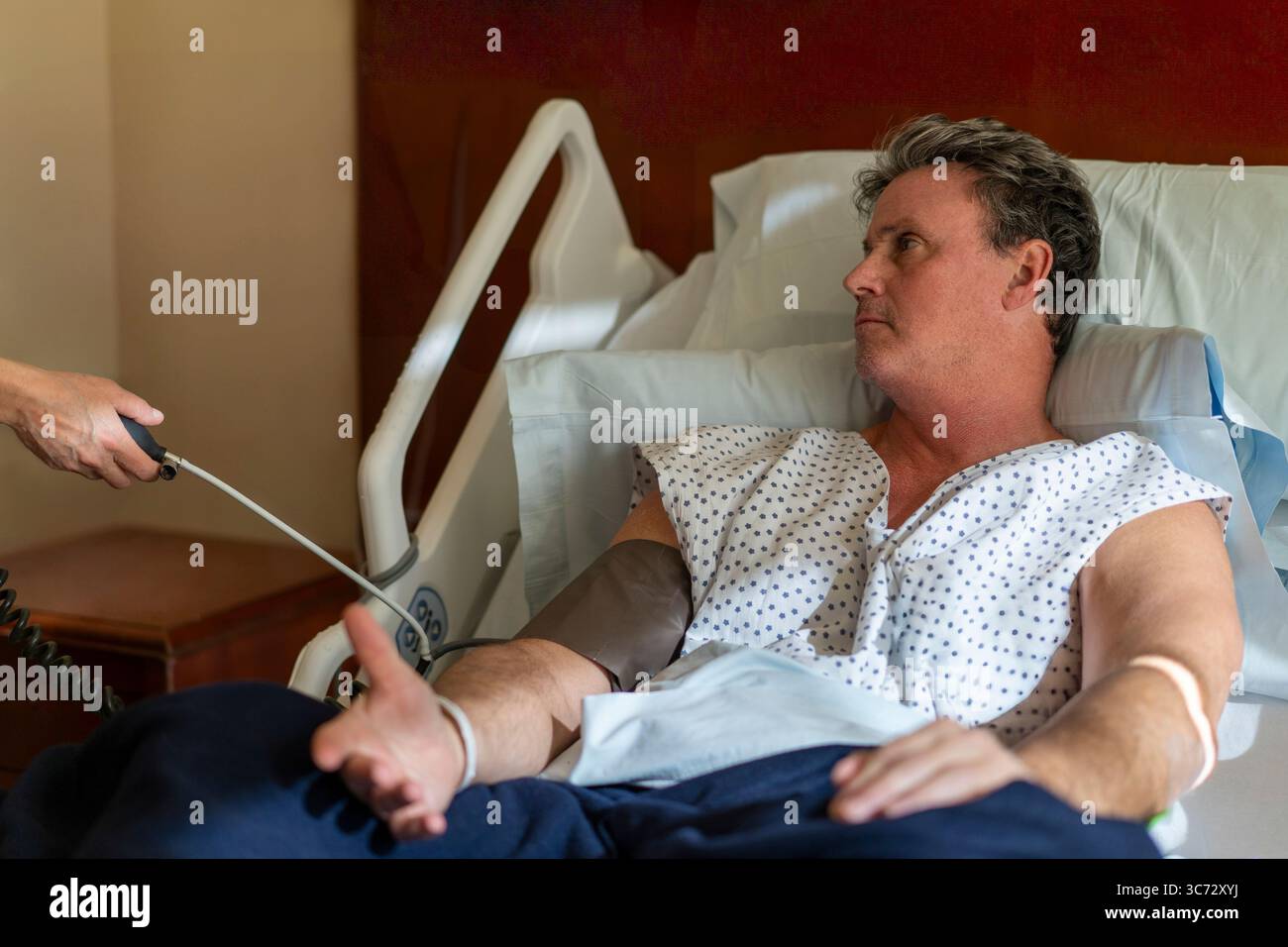 Misurazione della pressione sanguigna su un paziente ricoverato in ospedale. Foto Stock