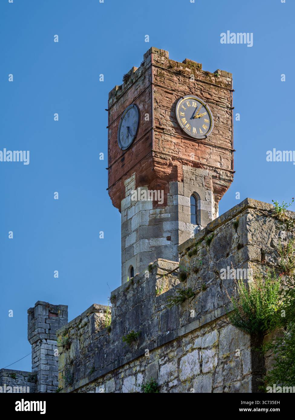 Torre dell'orologio del castello di Ruthin, Galles: Vista di una struttura a torre dell'orologio costruita in un'antica parete di confine in pietra Foto Stock