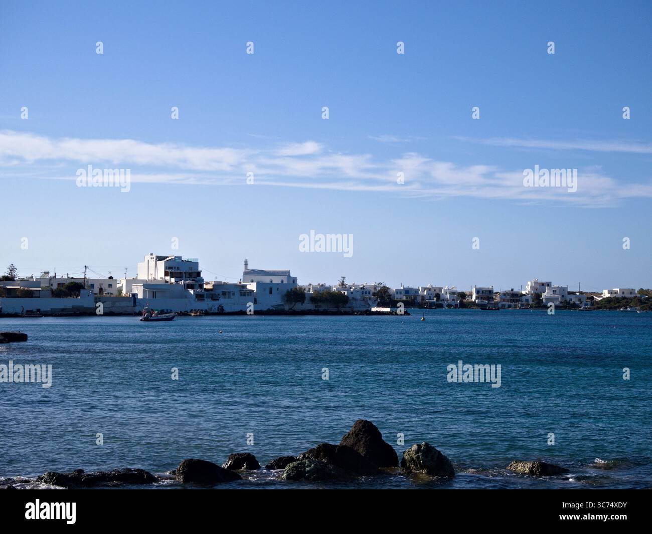 Case bianche sul lungomare nel villaggio di Apollonia, isola di Milos, Grecia, affacciate sul Mar Egeo sotto un cielo estivo azzurro. Foto Stock