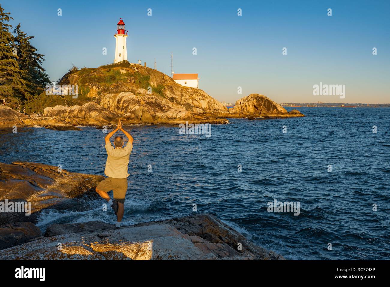 Lighthouse Yoga Serenity si trova al faro di Point Atkinson, dove un uomo trova il suo centro vicino all'iconica struttura. L'attuale faro era bui Foto Stock