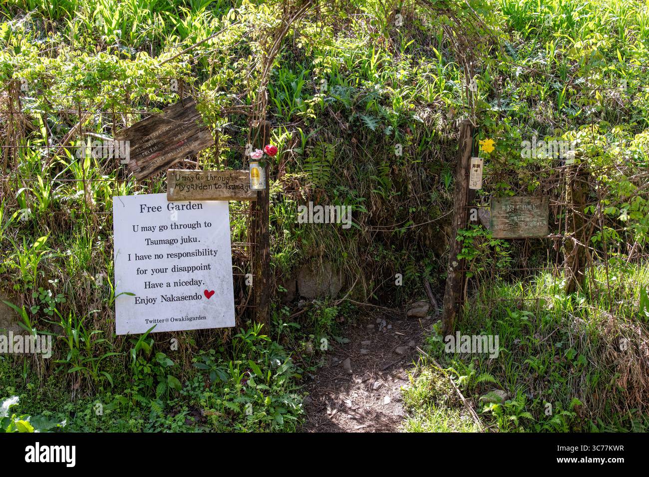 Magome, Giappone - 21 aprile 2025; cartelli all'ingresso del Giardino di Owaki lungo il sentiero Nakasendo appena fuori Magome-juku con artigianato, arte e fiori Foto Stock