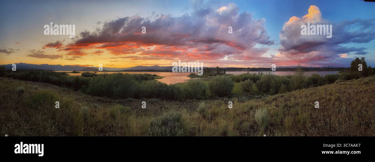 Una vista panoramica mozzafiato di un tramonto su un lago, con colori vivaci che dipingono il cielo e si riflettono sull'acqua. Foto Stock