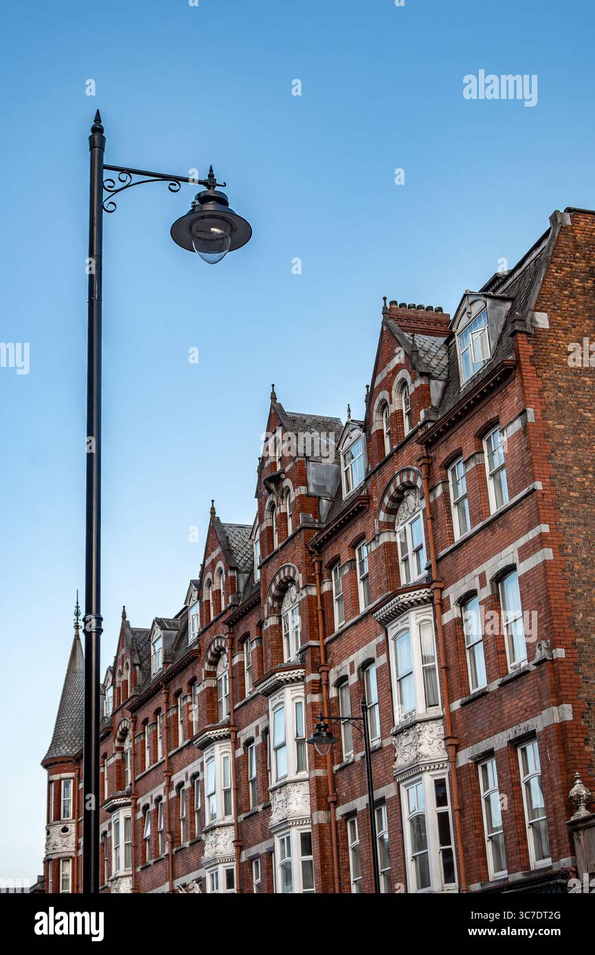 25 luglio 2025 Cork, Irlanda, affascinante architettura in mattoni con un lampione vintage crea un'atmosfera estetica Foto Stock