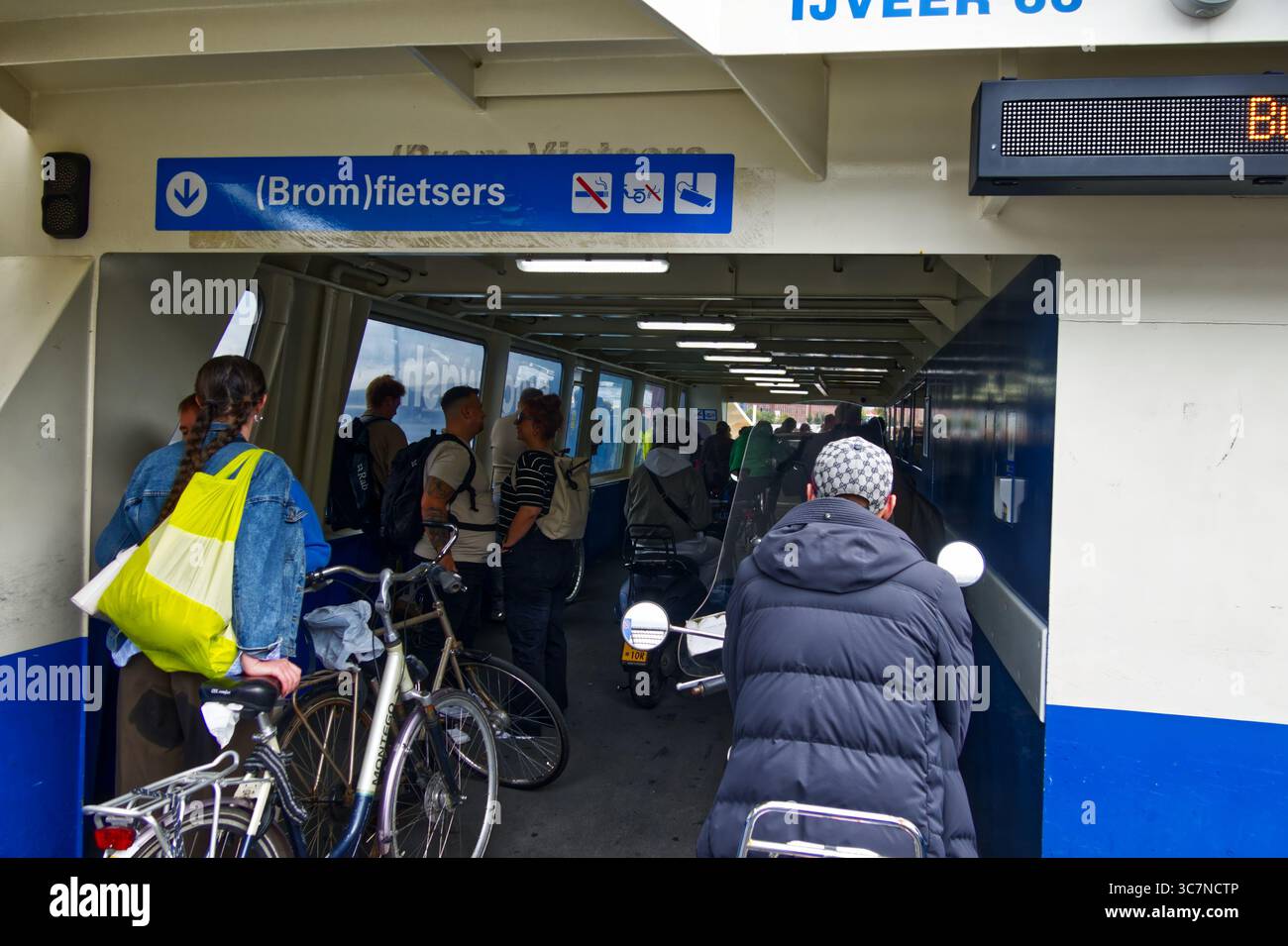 Amsterdam, paesi bassi, luglio 7,2025, turisti e pendolari si imbarcano su un traghetto ad amsterdam, portando con sé biciclette e ciclomotori, creando così Foto Stock