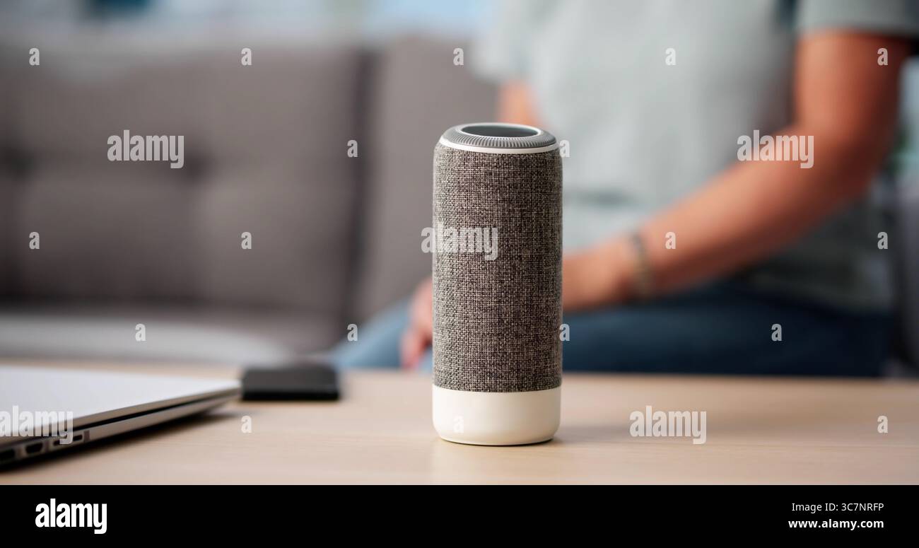 Donna anziana seduta da sola, che ascolta musica su Smart Speaker Foto Stock