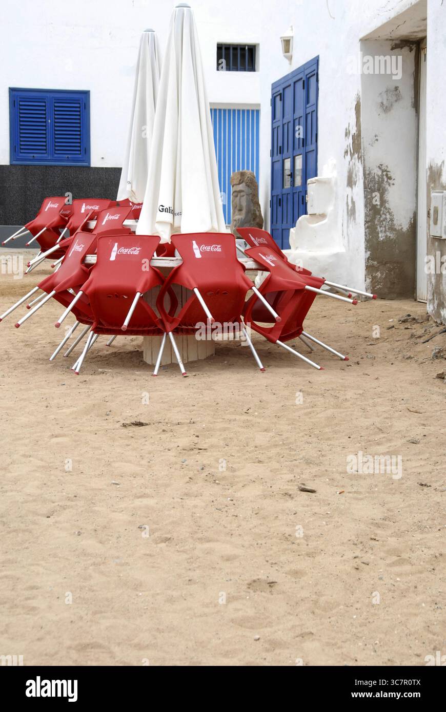 Sedie Coca-Cola rosse impilate e ombrelli chiusi a la Graciosa, Spagna, nel maggio 2011. Foto Stock