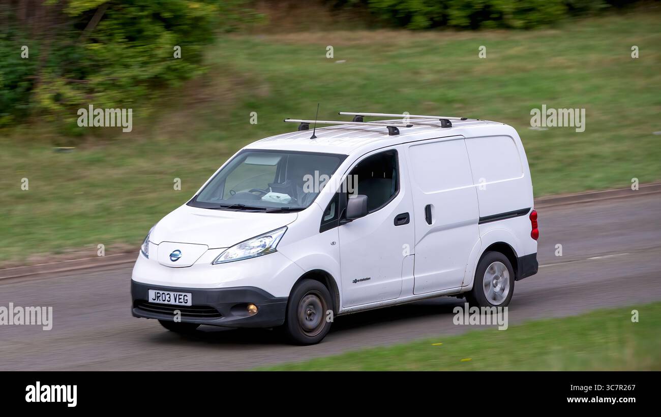 Milton Keynes,Bucks,UK - 1 agosto 2025: Furgone elettrico Nissan e-nv200 2018 bianco che guida su una strada britannica Foto Stock