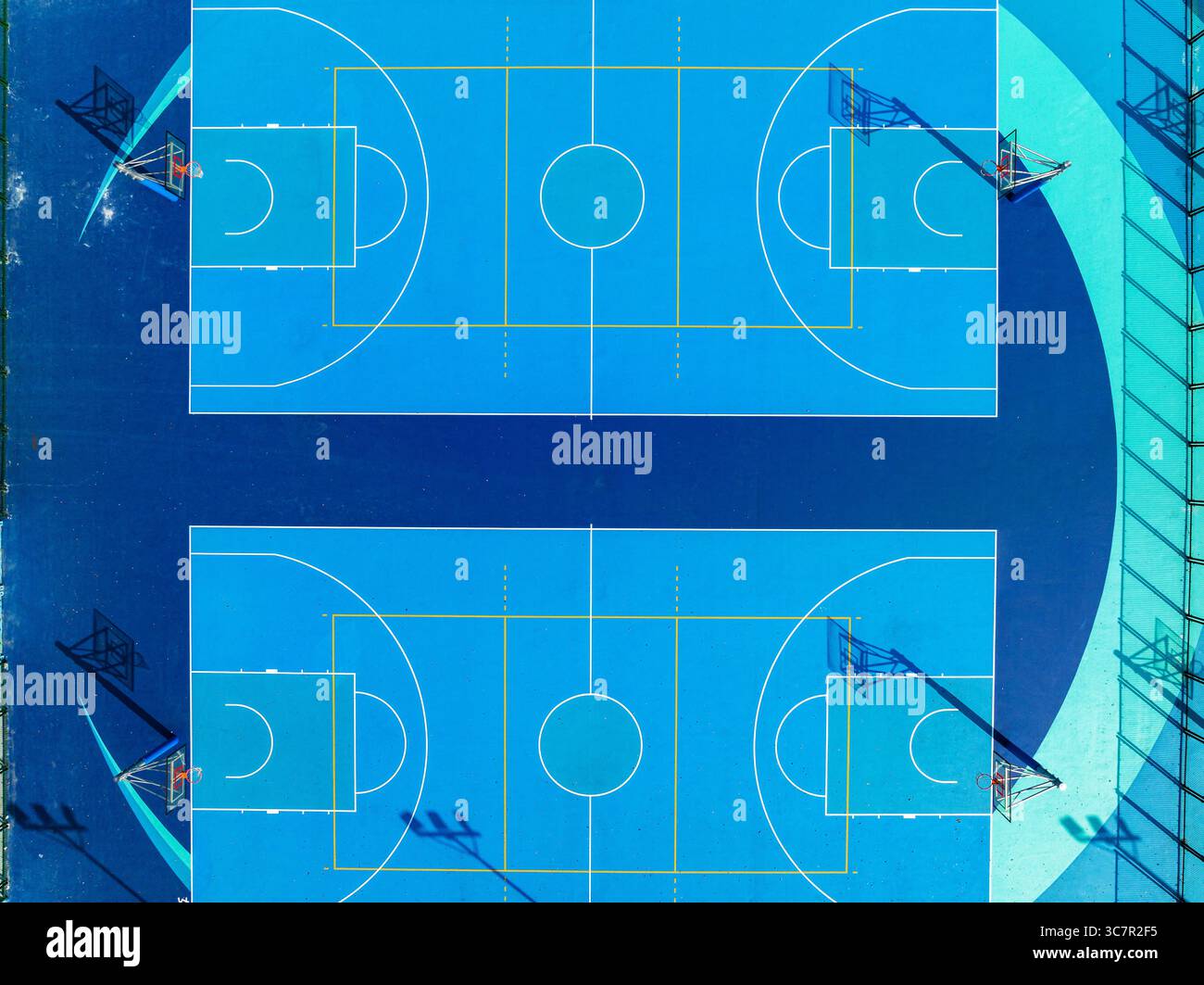 Vista dall'alto dei vivaci campi da pallacanestro blu nel complesso sportivo urbano all'aperto con disposizione simmetrica e motivi geometrici Foto Stock