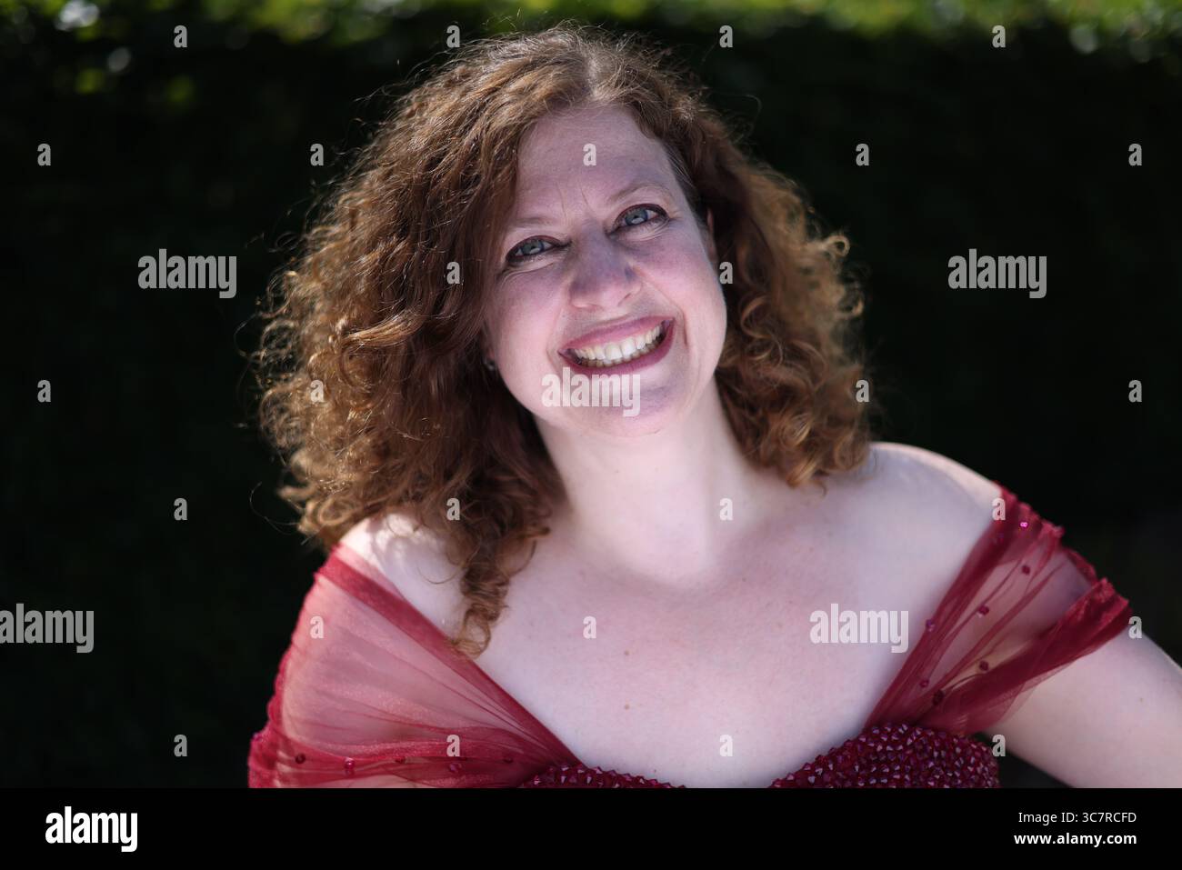 Donna in abito da sera rosso sorridente Foto Stock